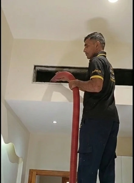 AC duct cleaning technician using vacuum machine to clean air ducts in Dubai